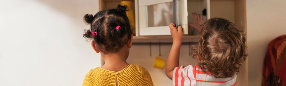 Two little kids playing in a miniature kitchen
